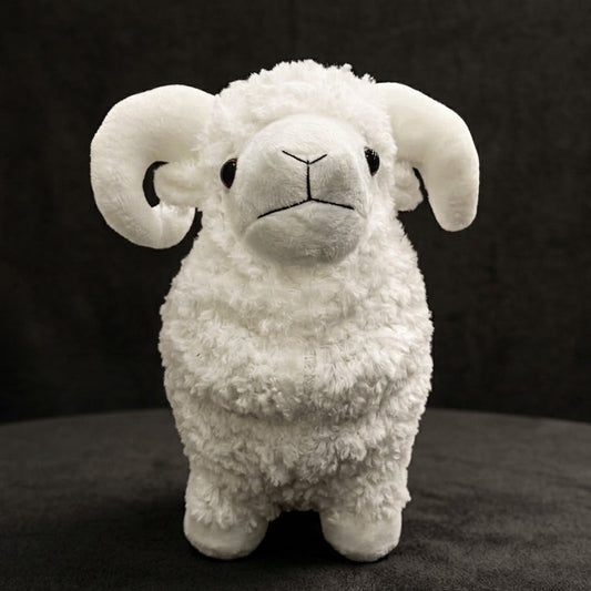 A white plush toy sheep with curly wool and curled back horns, standing against a dark textured background.